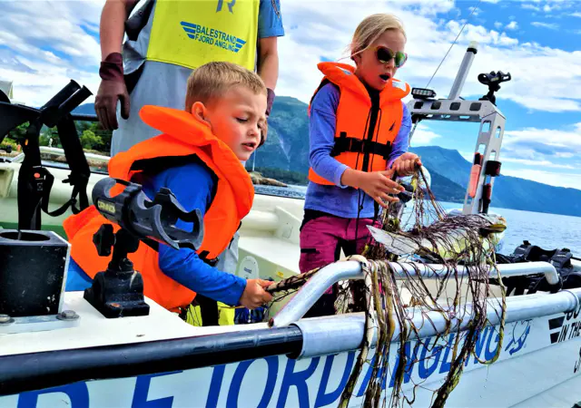Captain Tor walking on the water in Sognefjord, blue sky and white clouds and pointing to the new direction: The Human Edge.